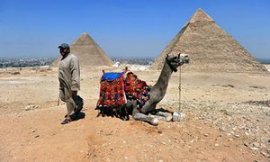 a person waits to provide tourists camel rides at the pyramids in Giza